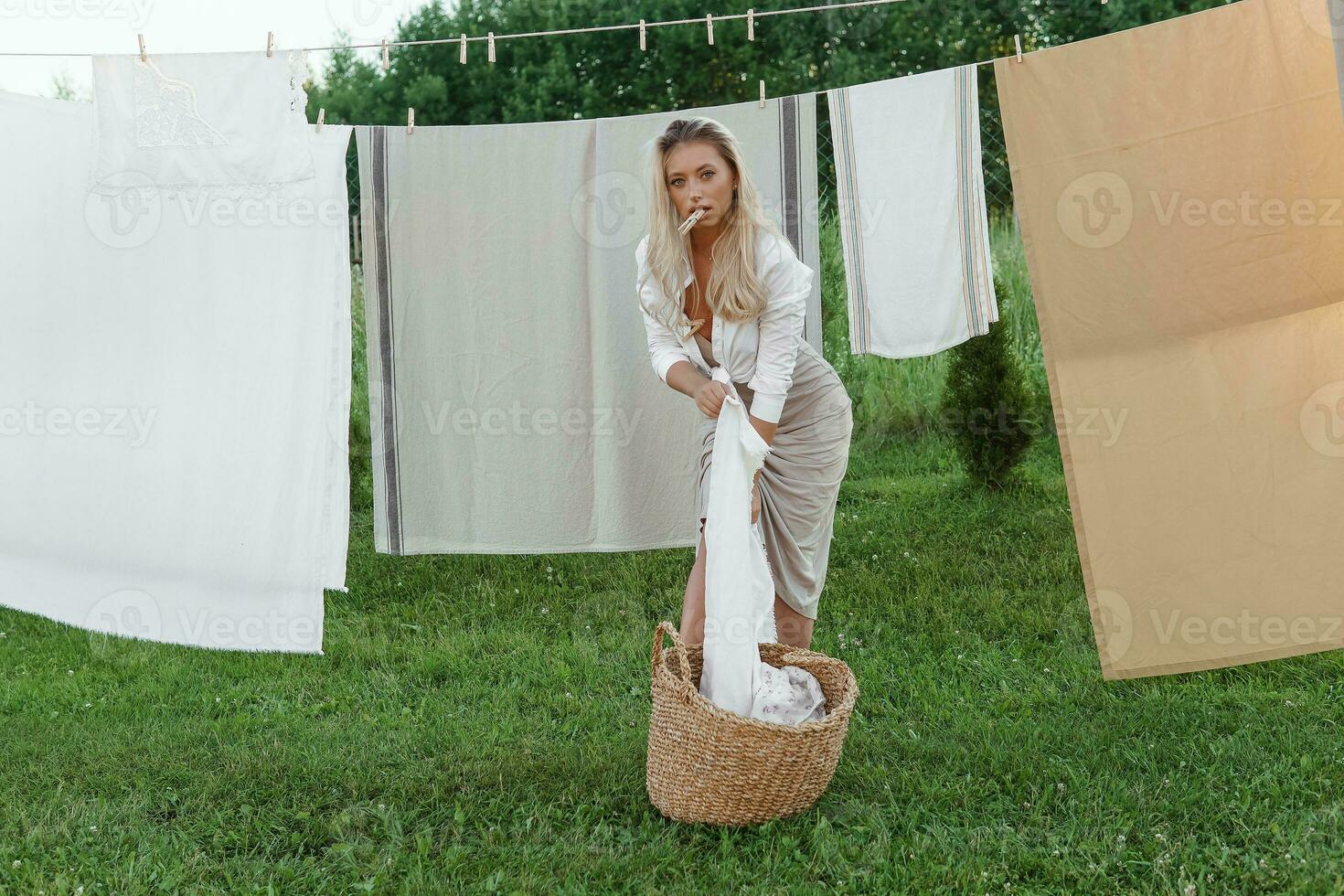 lavanderia dia. uma mulher trava linho e toalhas em uma árvore dentro a pátio do uma Vila casa. foto
