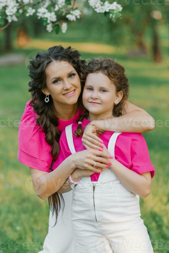 uma jovem lindo mãe é feliz e abraços dela filha, quem é sorridente foto