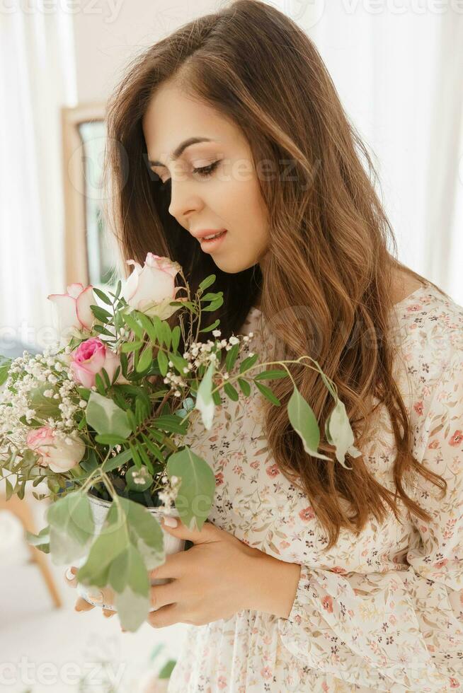 uma cabelos castanhos mulher com grandes cabelo é tendo café da manhã dentro uma lindo floral localização. Primavera retrato. foto
