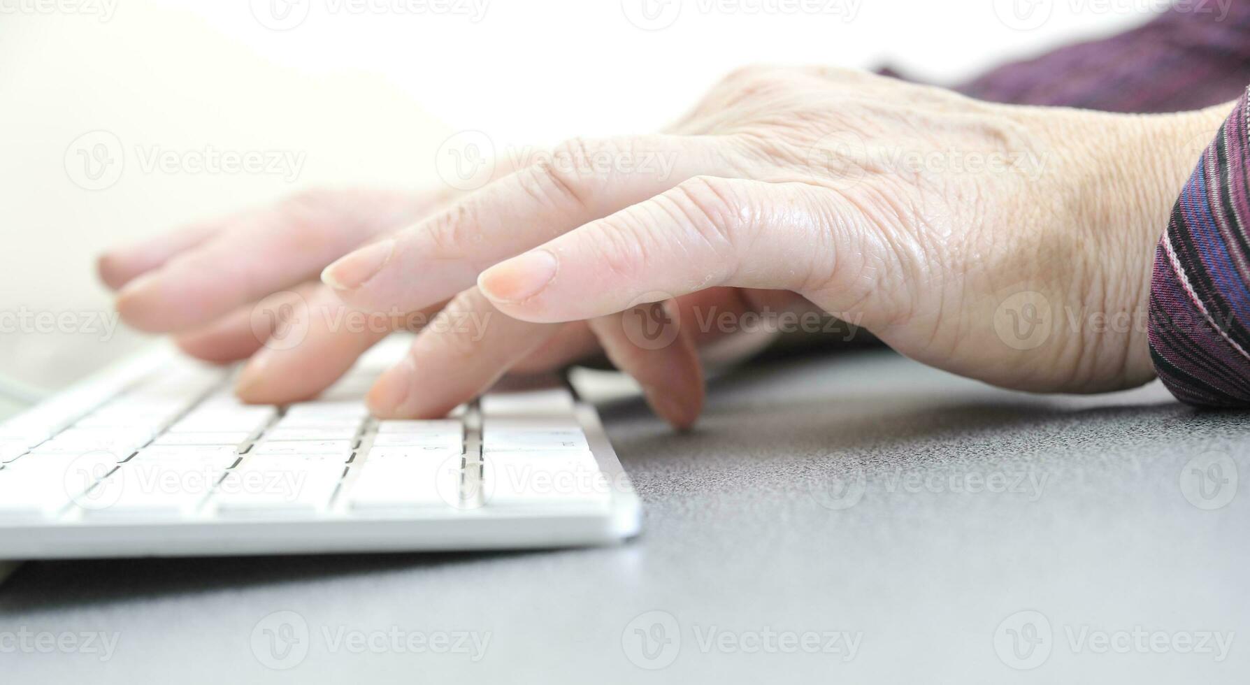 mãos do a velho fêmea digitando em a teclado, isolado em branco, fechar-se. foto