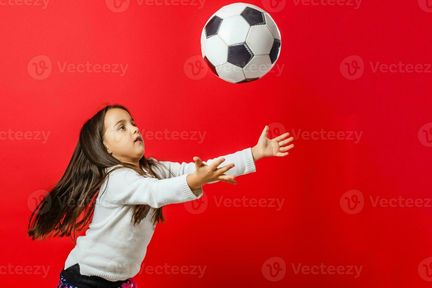 pequeno menina com a bola sobre vermelho background foto