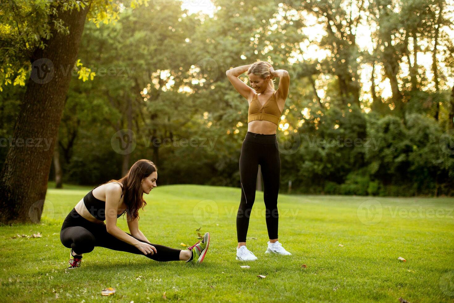 dois bonita jovem mulheres alongamento dentro a parque foto