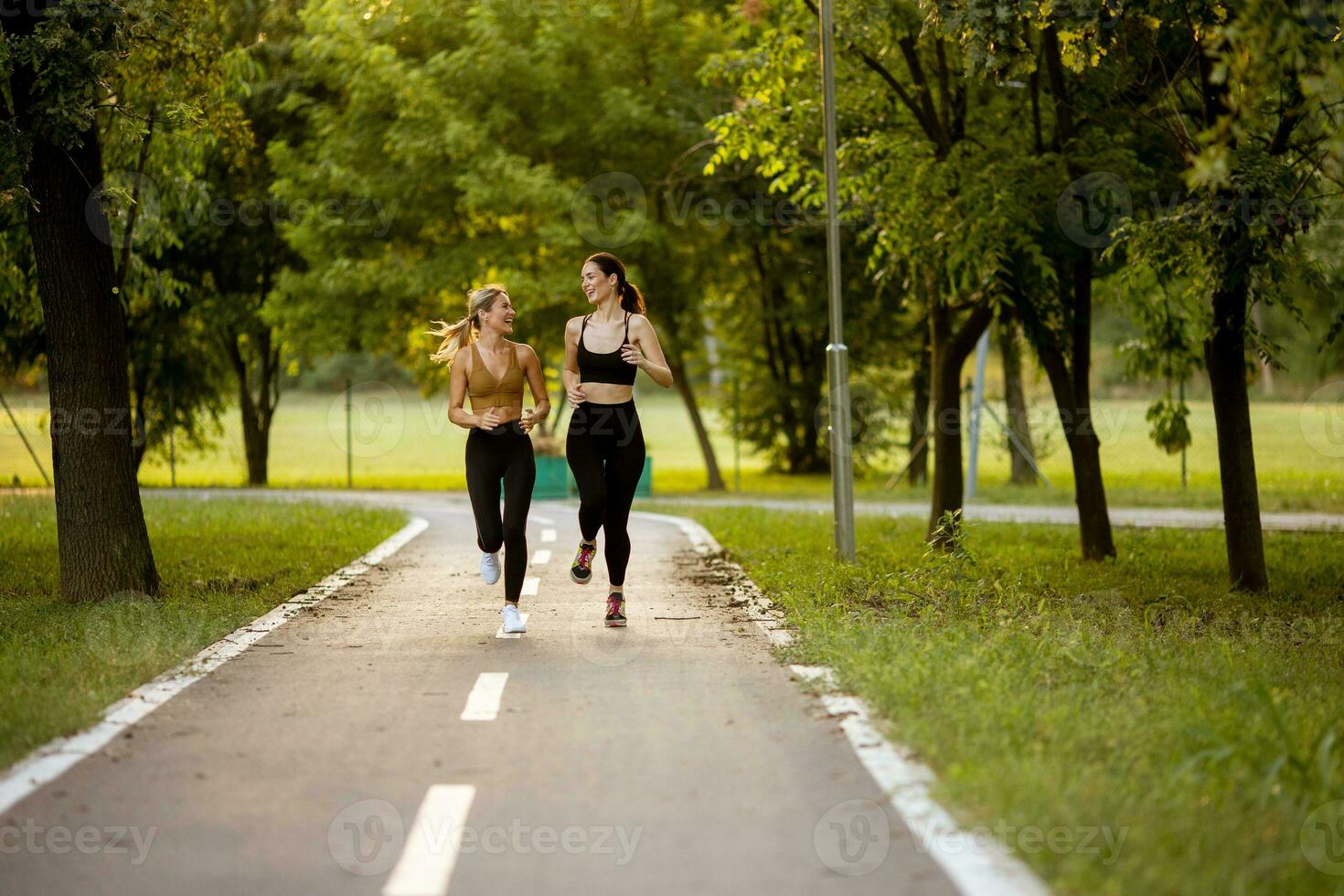dois bonita jovem mulheres corrida em a faixa dentro a parque foto