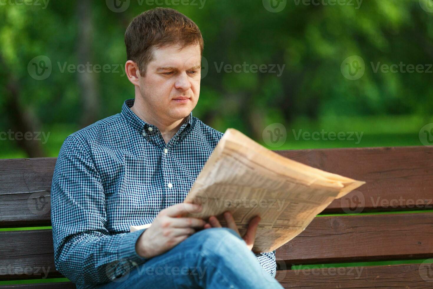 homem lê jornal em Banco dentro a parque foto