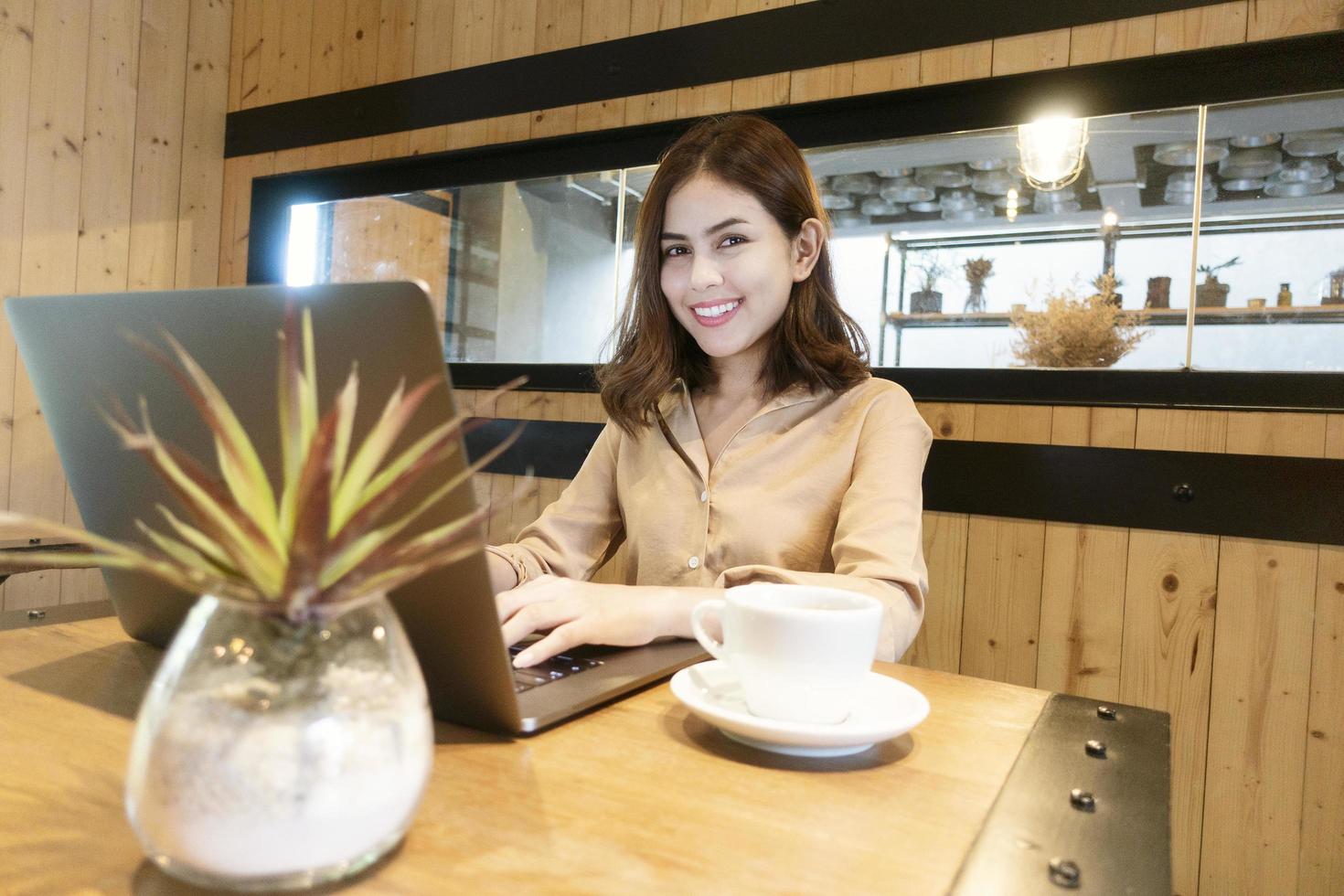 linda mulher de negócios está trabalhando com seu laptop na cafeteria foto