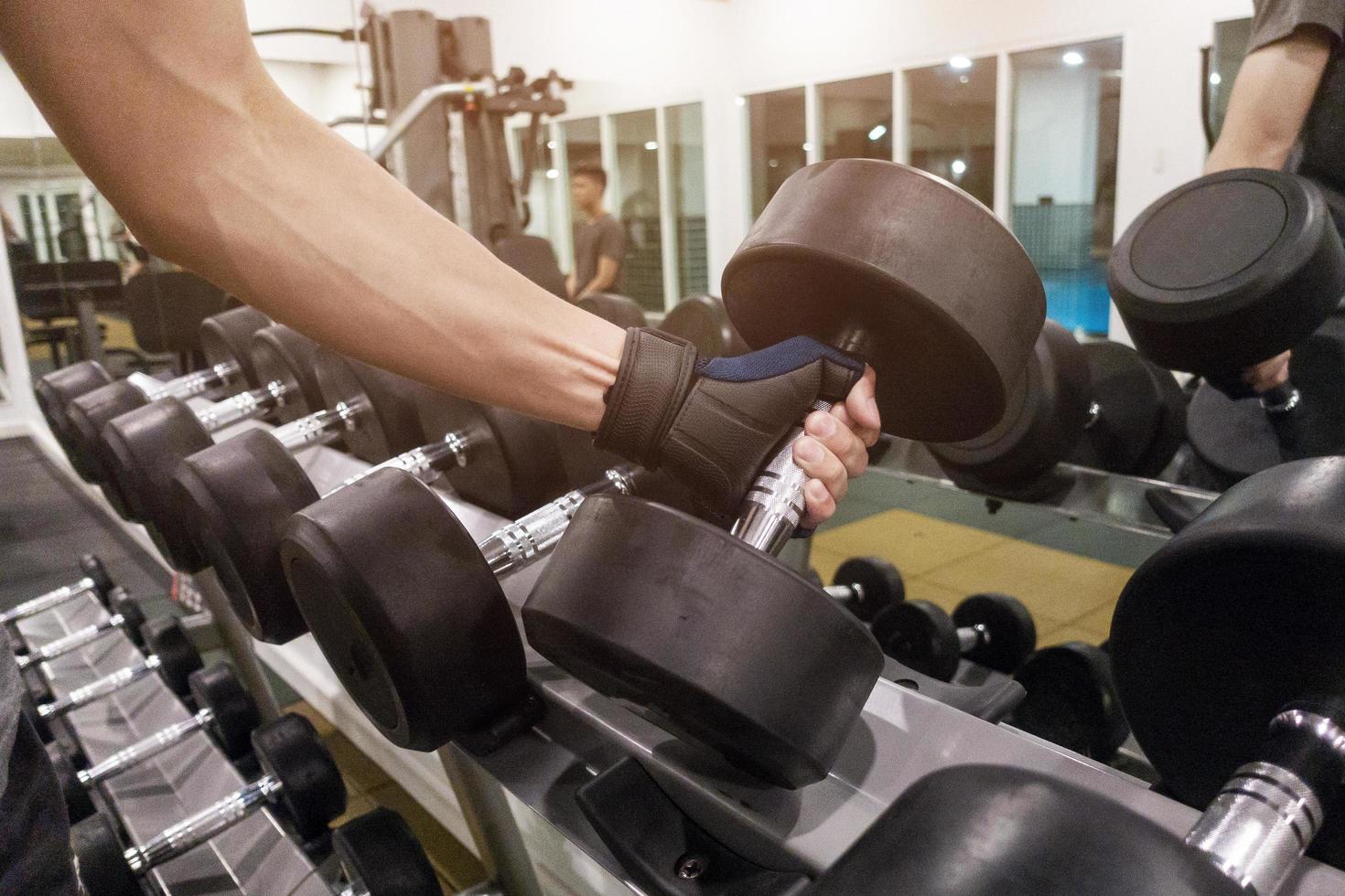 mão humana segurando halteres na academia foto