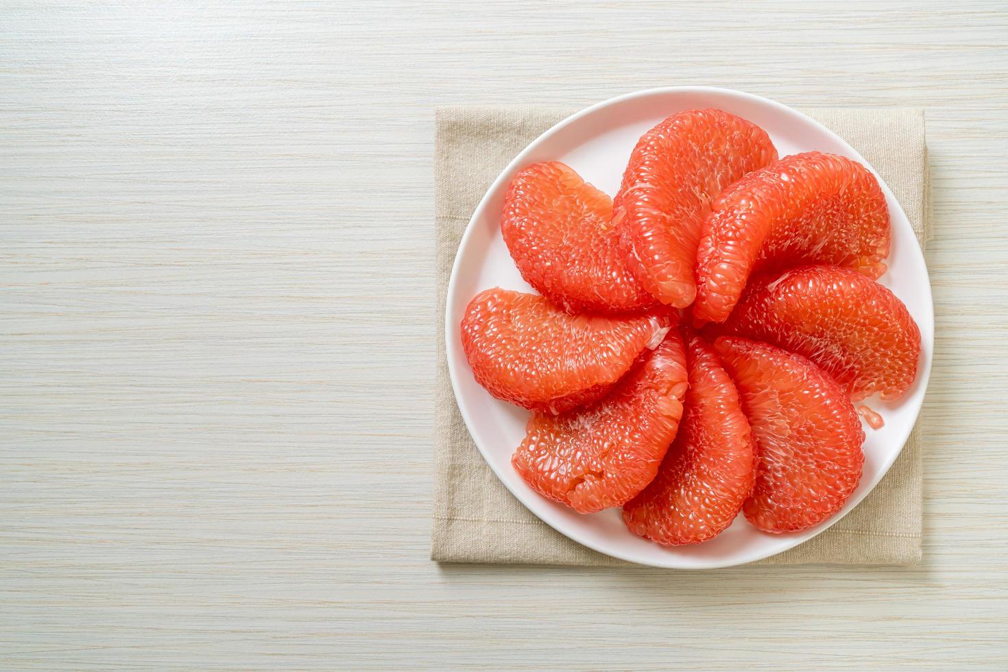 pomelo vermelho fresco ou toranja no prato foto