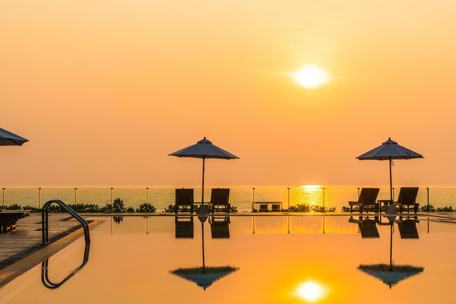 lindo guarda-sol e cadeira ao redor da piscina no hotel e resort foto