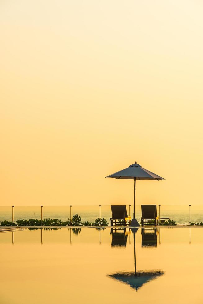 lindo guarda-sol e cadeira ao redor da piscina no hotel e resort foto