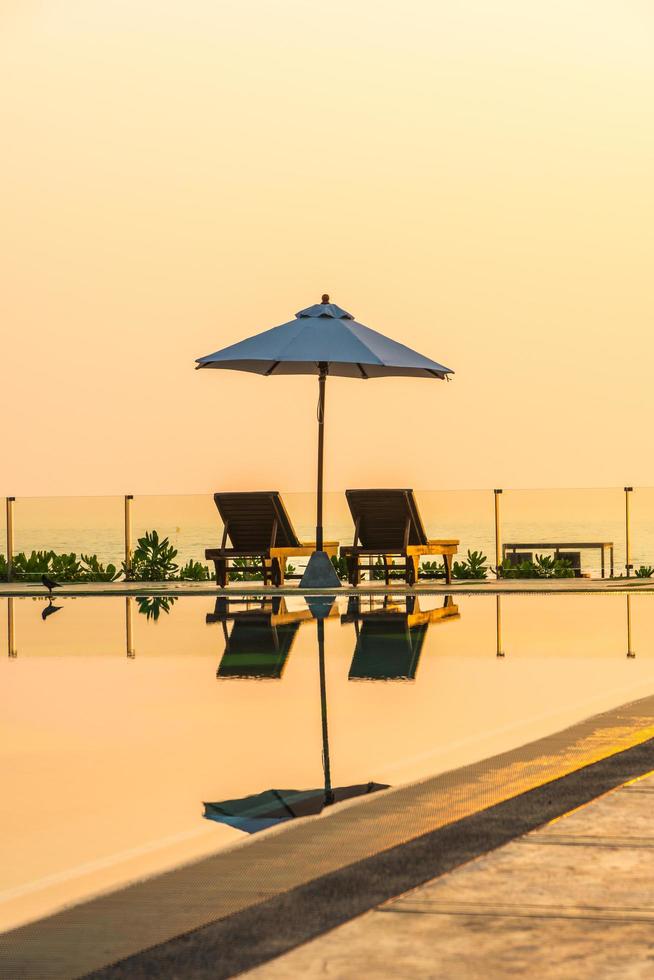 lindo guarda-sol e cadeira ao redor da piscina no hotel e resort foto