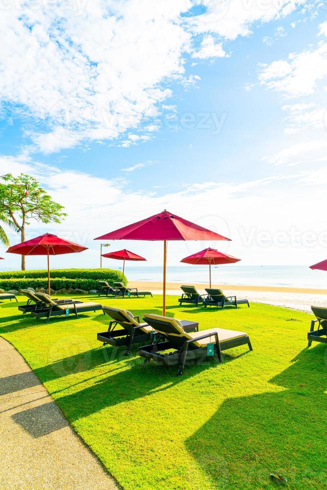 guarda-sóis e cadeiras de praia vermelhos com fundo de praia do mar e céu azul e luz do sol foto