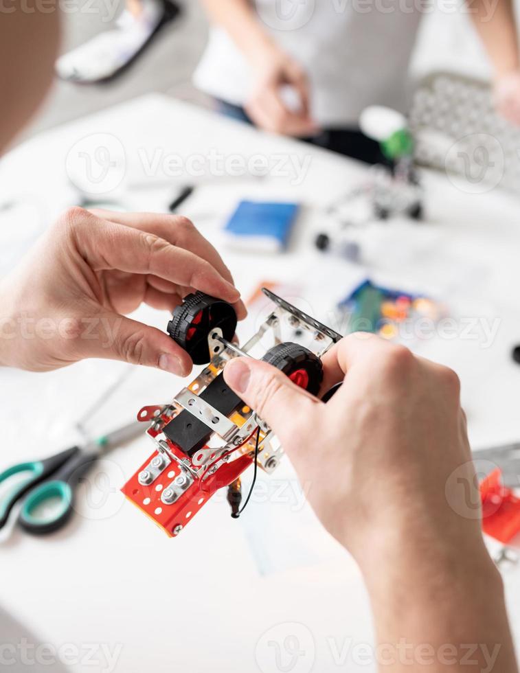 mãos masculinas construindo carros robôs na oficina foto