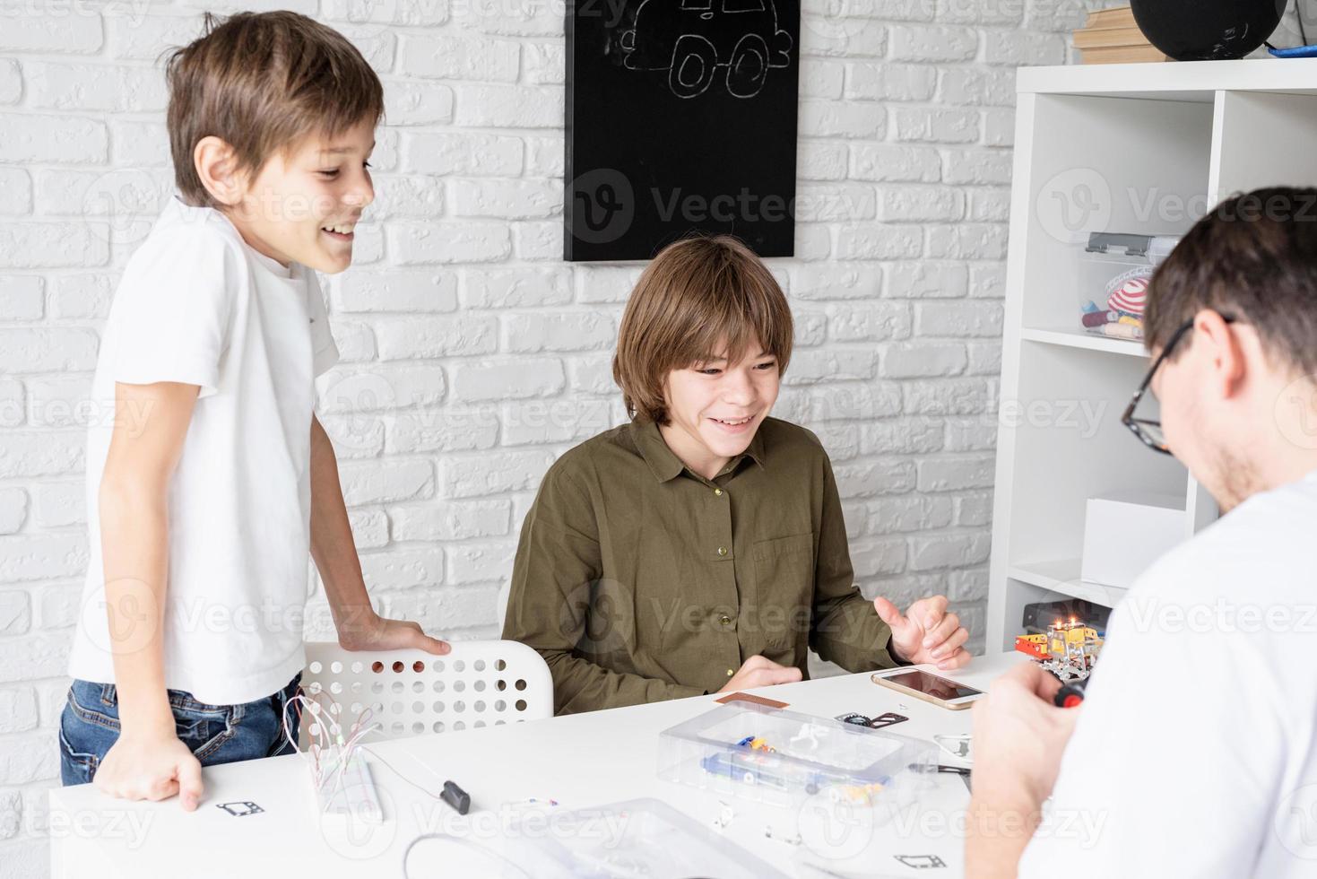 meninos se divertindo construindo carros robôs na oficina foto