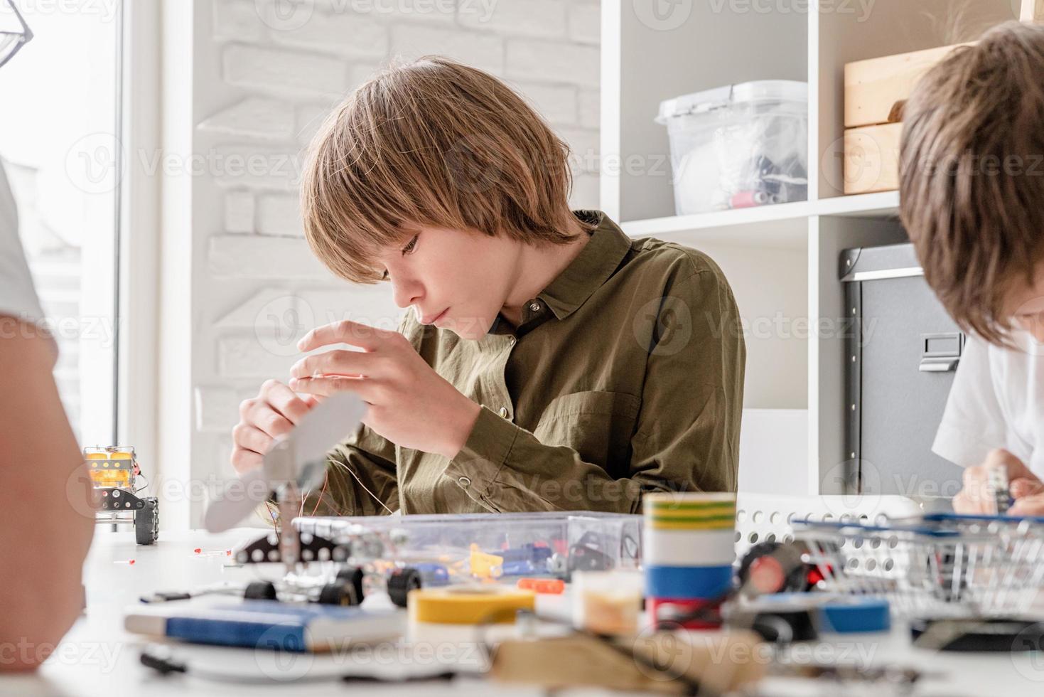 meninos se divertindo construindo carros robôs na oficina foto