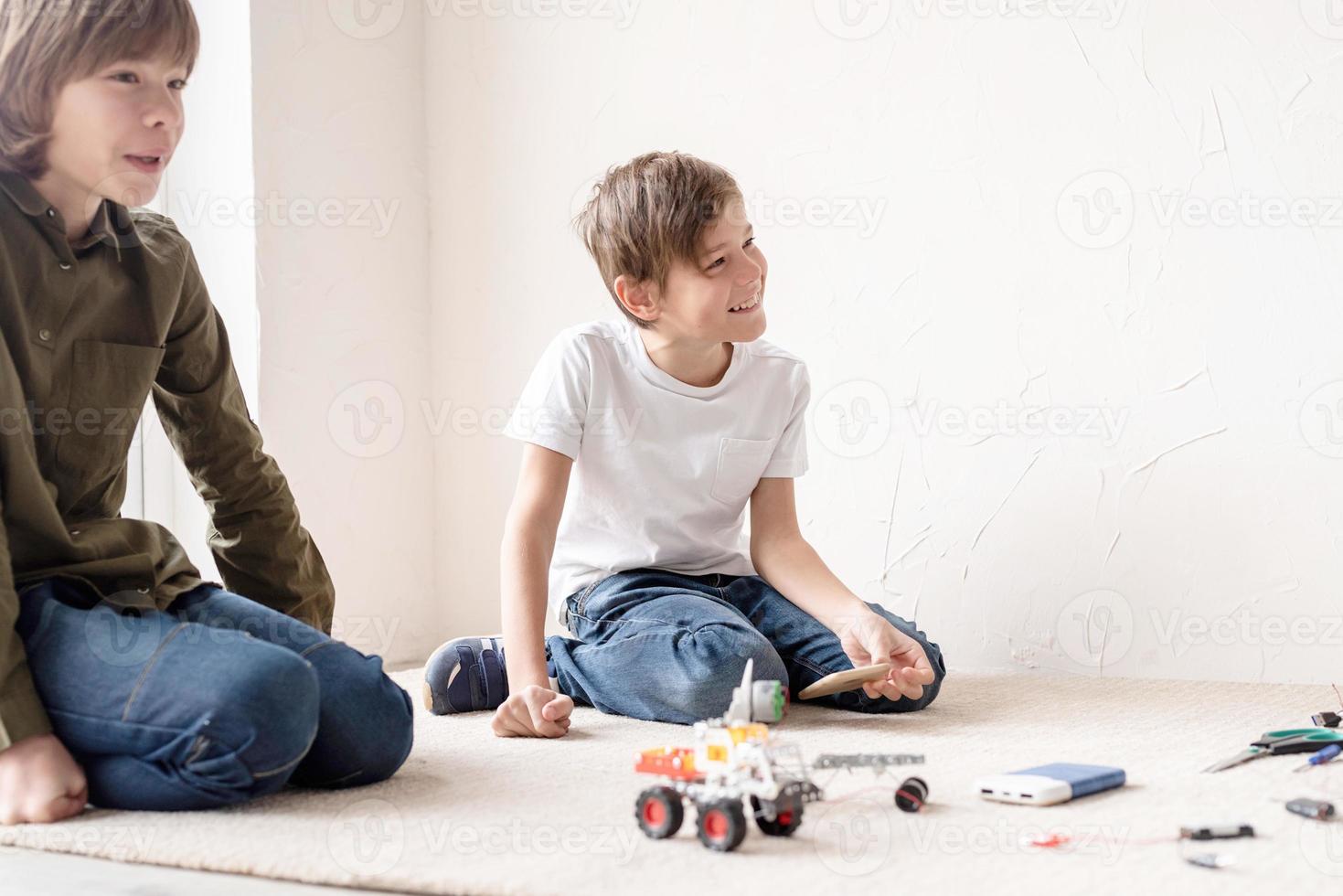 meninos e professor se divertindo construindo carros robôs na oficina, vista de cima foto