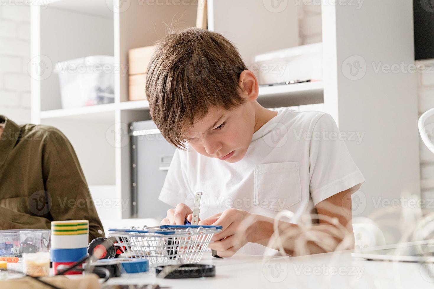 meninos se divertindo construindo carros robôs na oficina foto