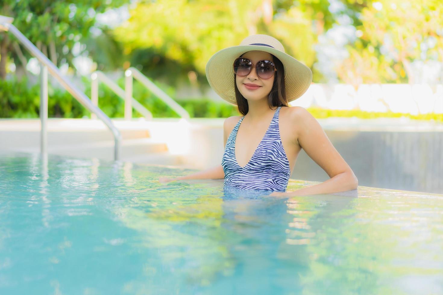 lindas jovens mulheres asiáticas sorriso feliz relaxando ao redor da piscina ao ar livre em hotel resort para viagens de férias foto