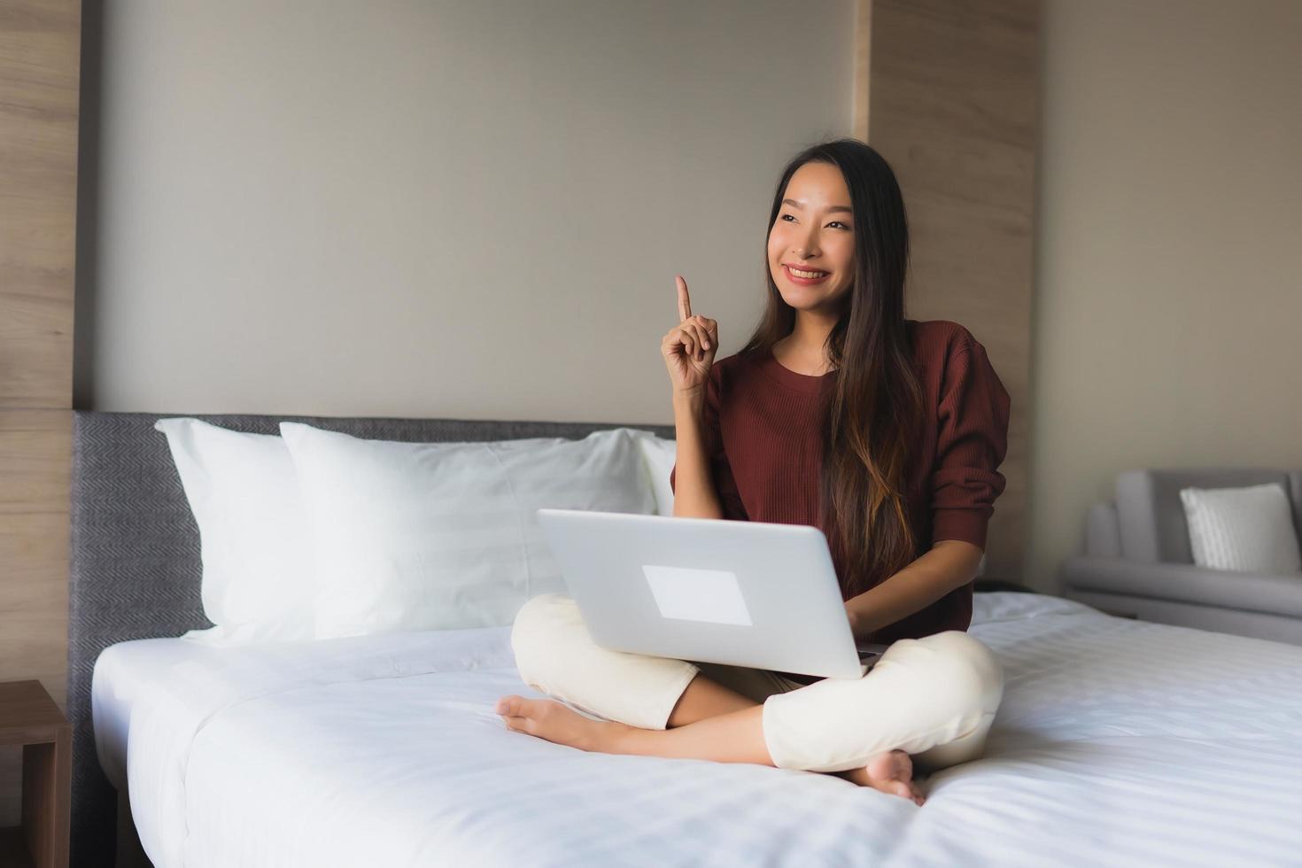 retrato de belas jovens mulheres asiáticas usando computador e telefone celular na cama foto