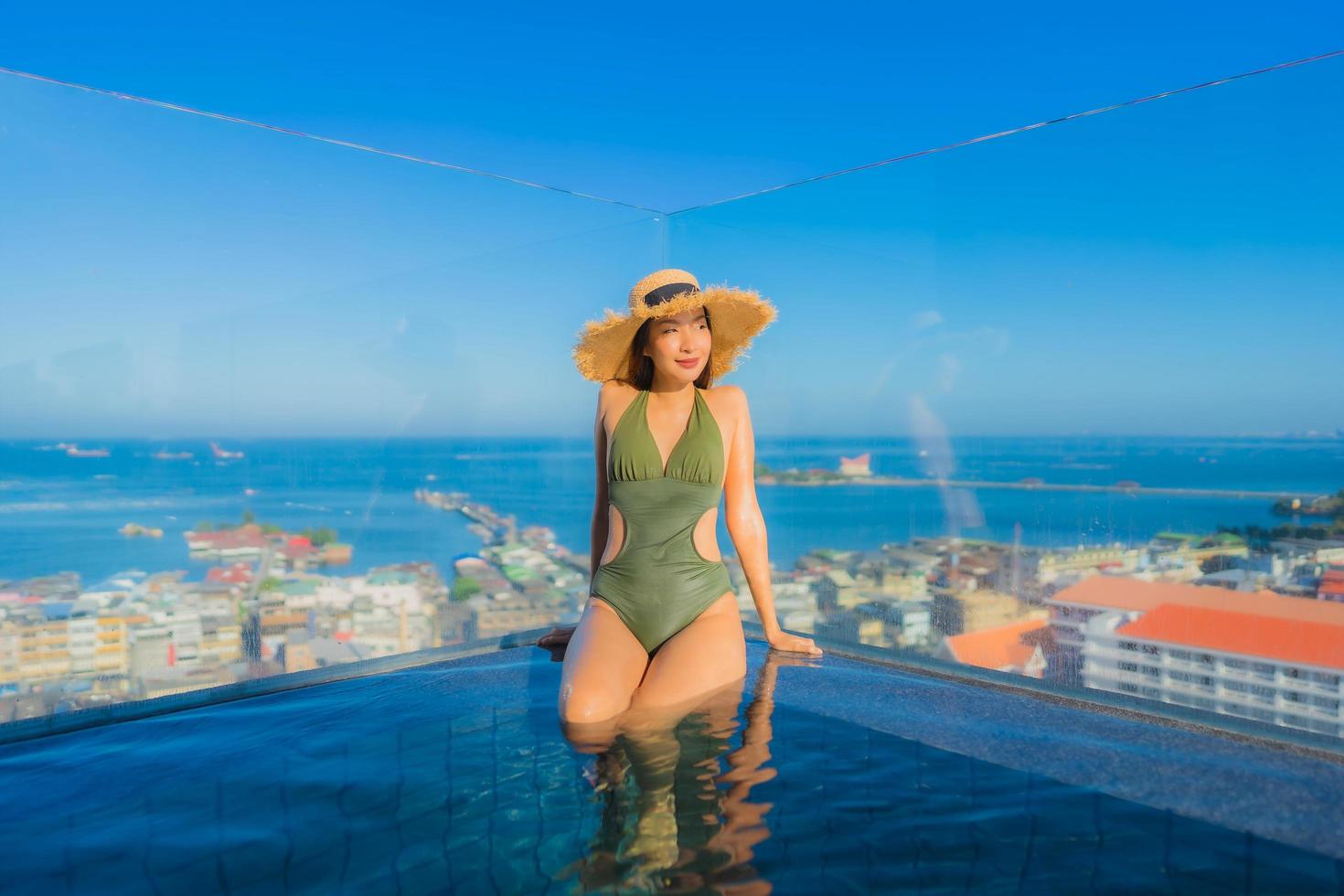 lindas jovens mulheres asiáticas sorriso feliz relaxando ao redor da piscina ao ar livre em hotel resort para viagens de férias foto