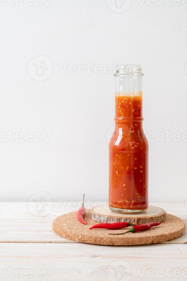 pimenta ou molho de pimenta em garrafa e jarra com fundo de madeira foto