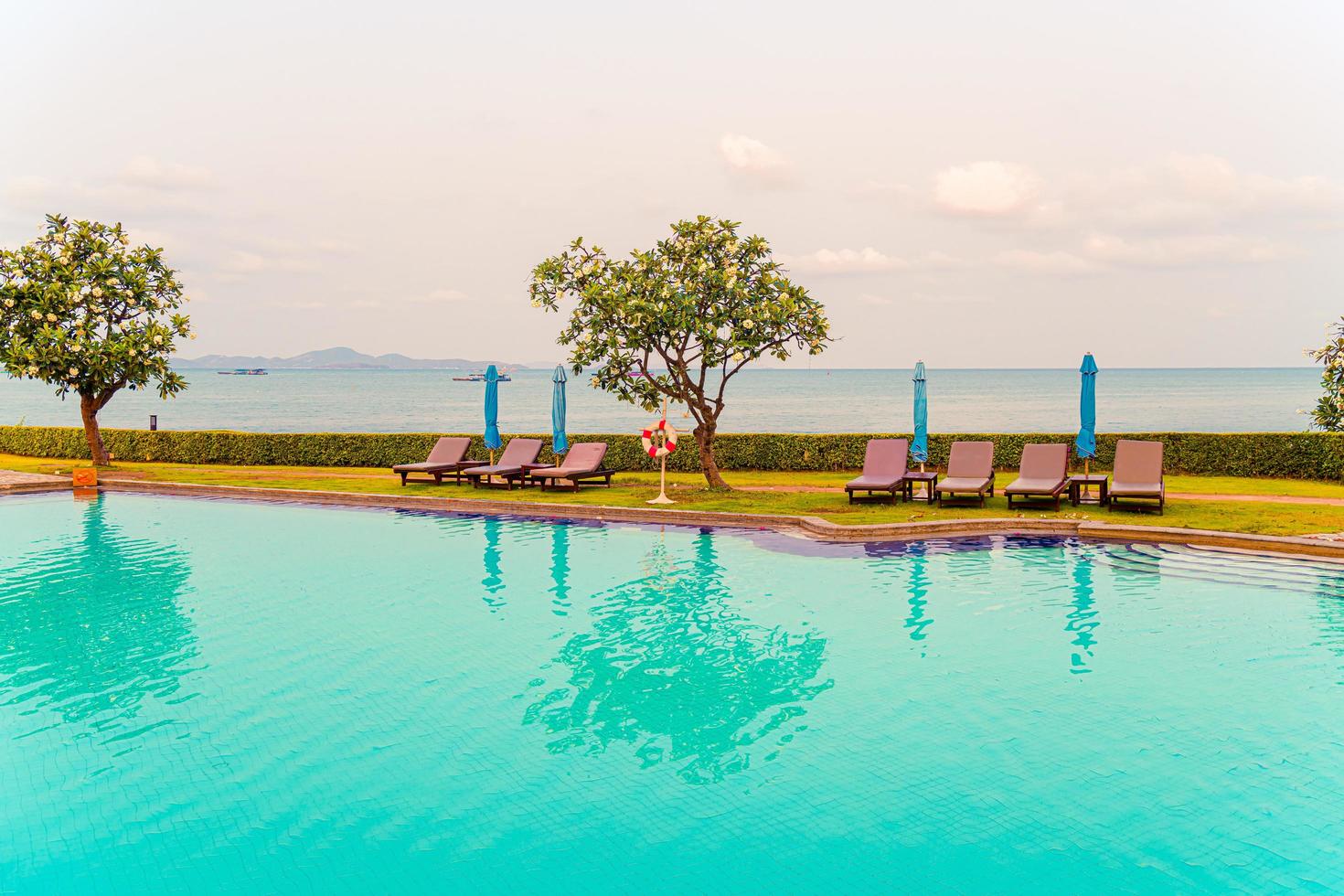 cadeira de piscina ou piscina com cama com guarda-chuva ao redor da piscina foto