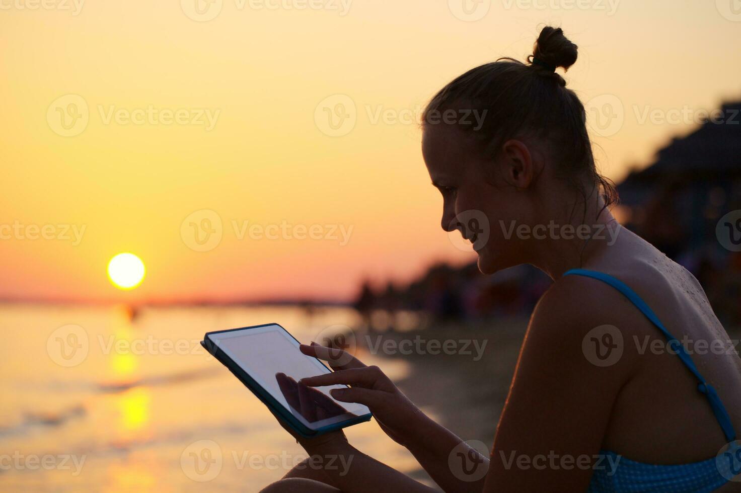 sorridente mulher usando almofada em de praia às pôr do sol foto