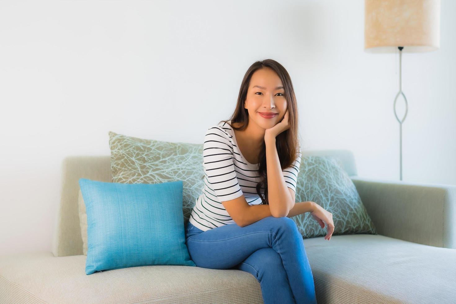 retrato linda jovem asiática sorrindo feliz no sofá foto