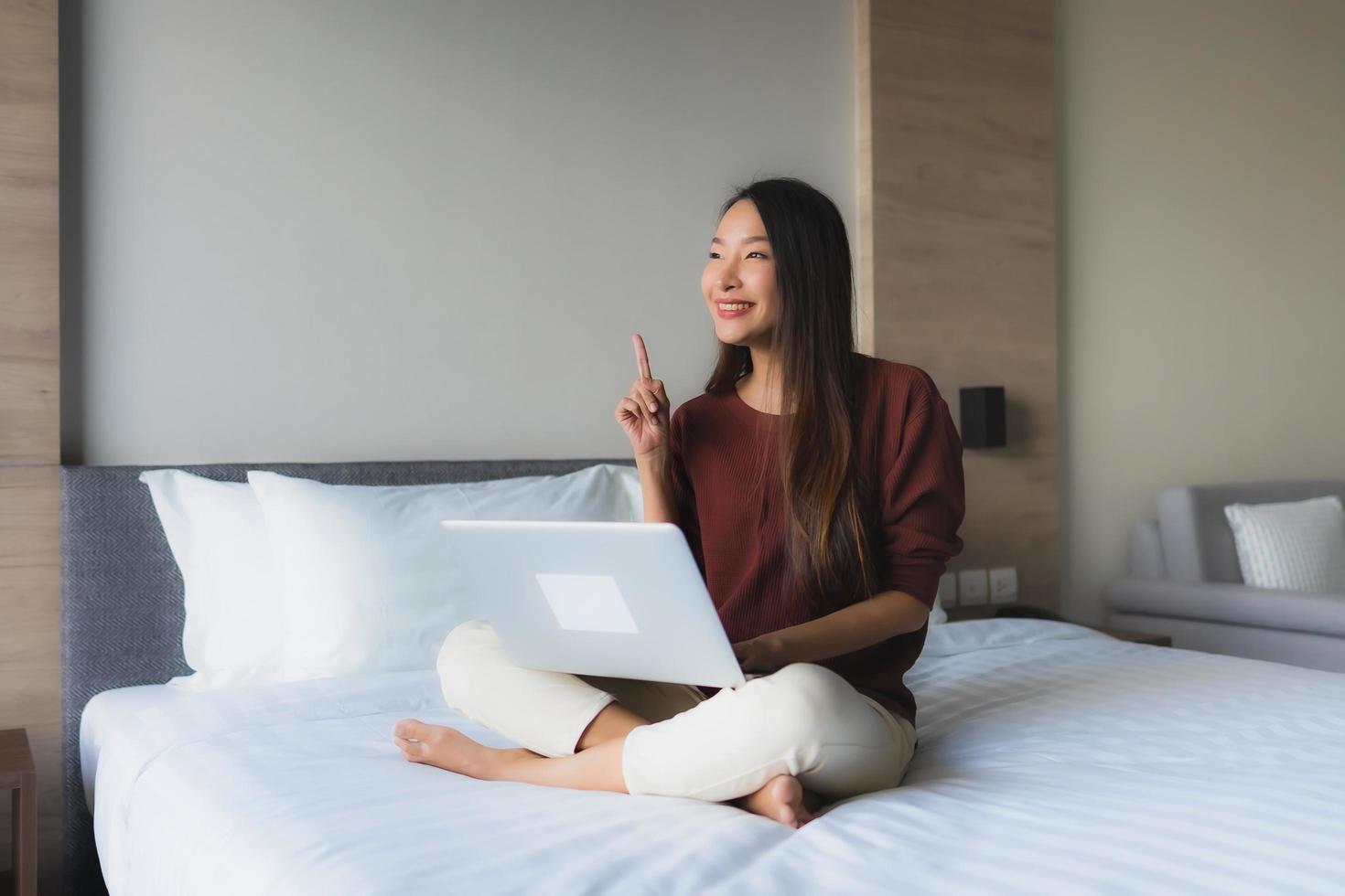 retrato de belas jovens mulheres asiáticas usando computador e telefone celular na cama foto