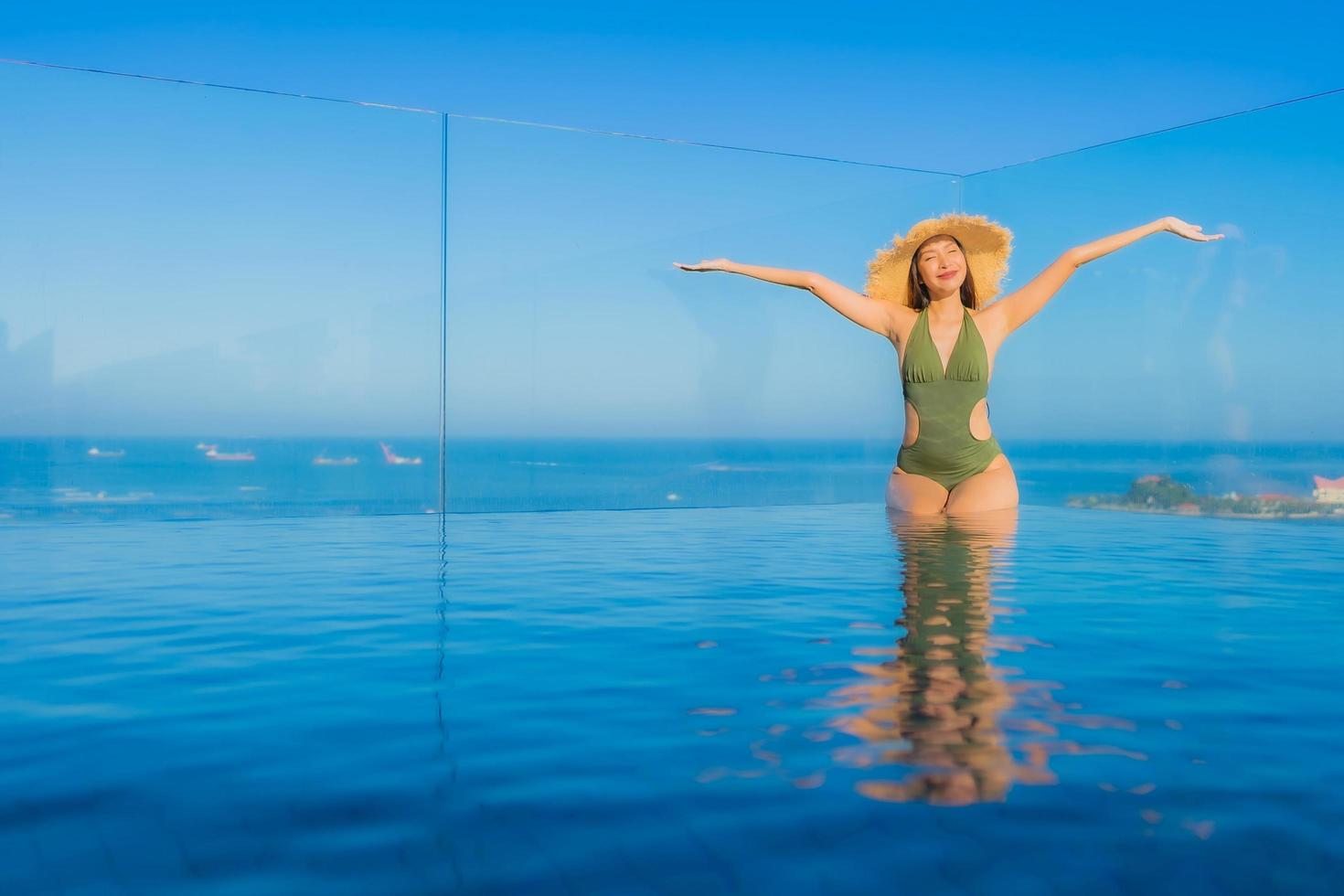 lindas jovens mulheres asiáticas sorriso feliz relaxando ao redor da piscina ao ar livre em hotel resort para viagens de férias foto