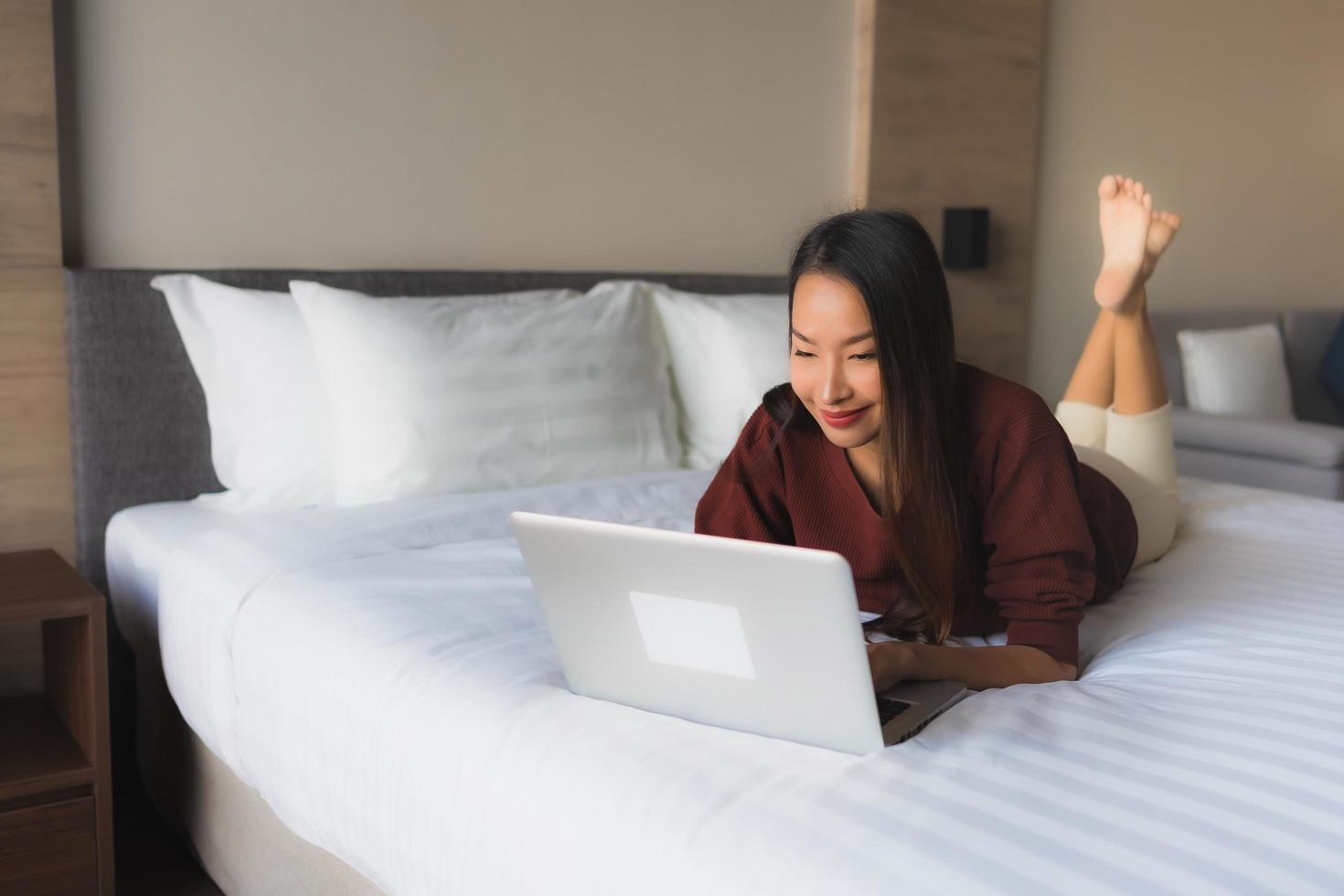 retrato de belas jovens mulheres asiáticas usando computador e telefone celular na cama foto