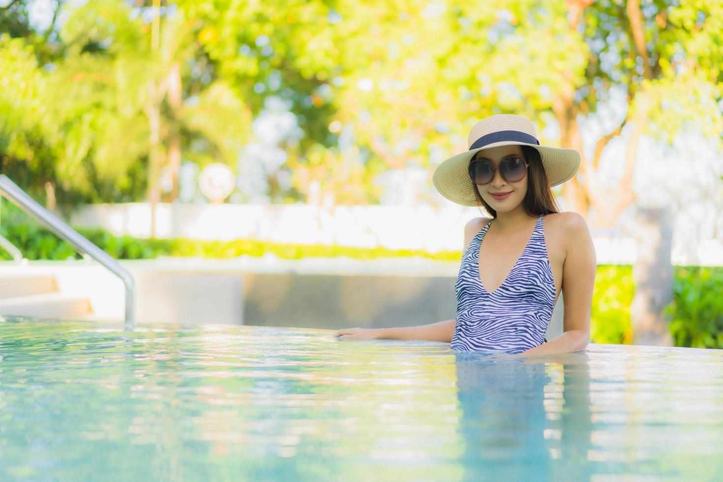 lindas jovens mulheres asiáticas sorriso feliz relaxando ao redor da piscina ao ar livre em hotel resort para viagens de férias foto