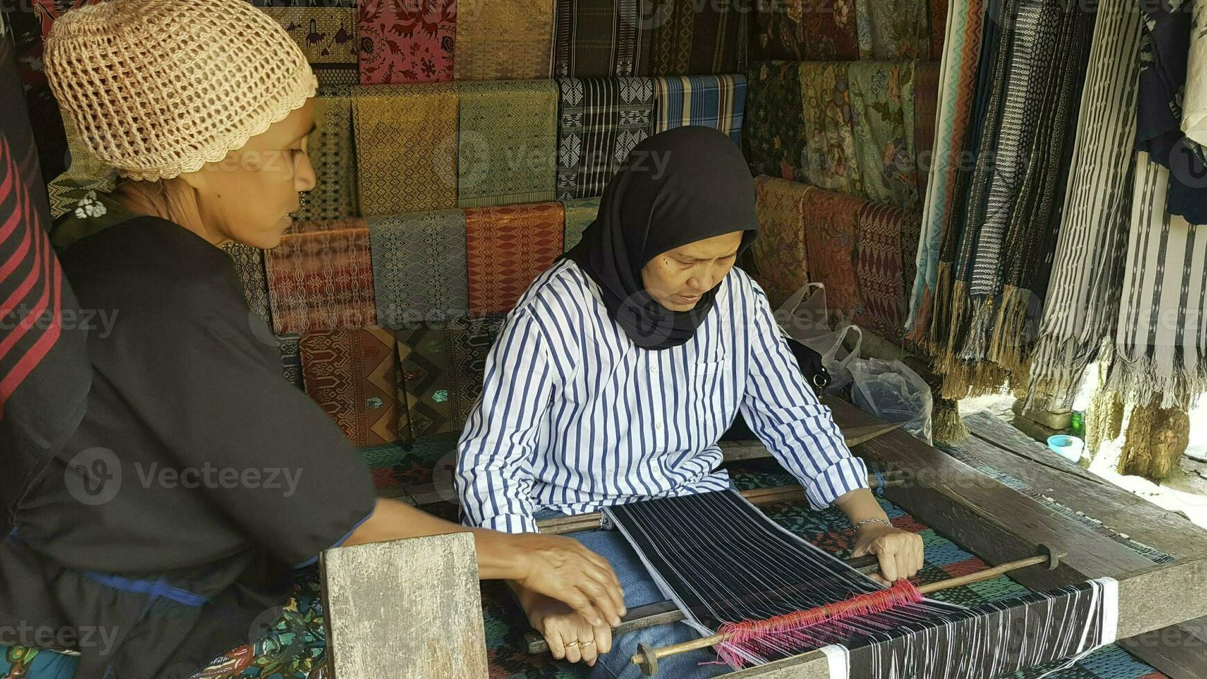 mulher tecelagem seda pano e kain cantora às a mercado dentro lombok, Indonésia foto