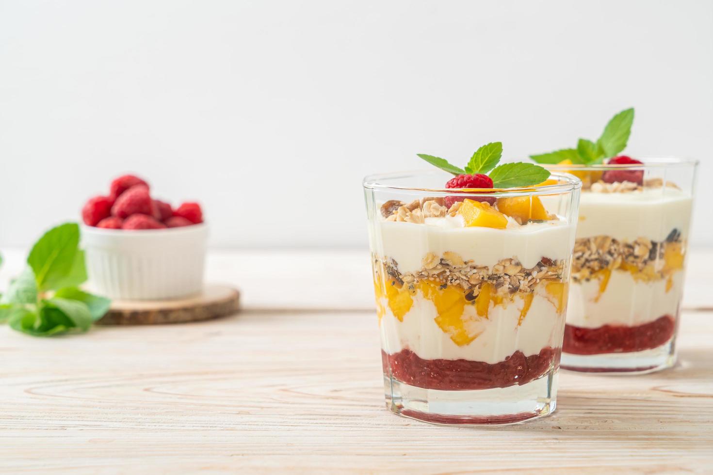 manga fresca caseira e framboesa fresca com iogurte e granola - estilo de comida saudável foto