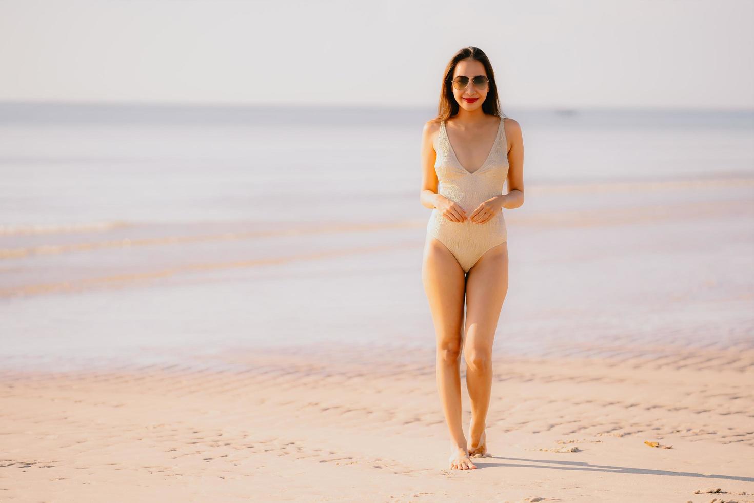 retrato jovem linda mulher asiática caminhar sorriso feliz na praia, mar, oceano, com, óculos escuros foto