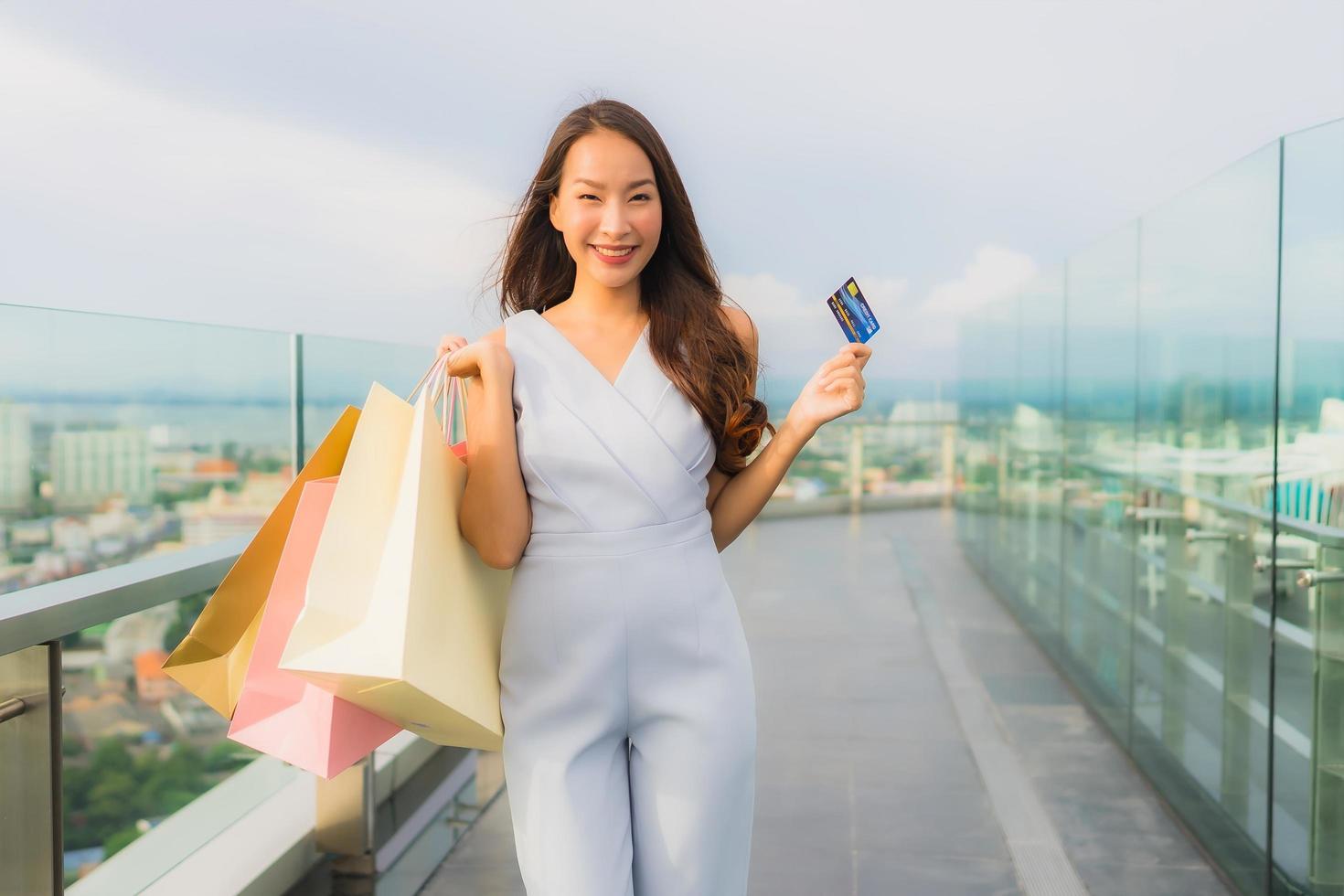 retrato linda jovem asiática feliz e sorrindo com cartão de crédito para sacola de compras da loja de departamentos foto