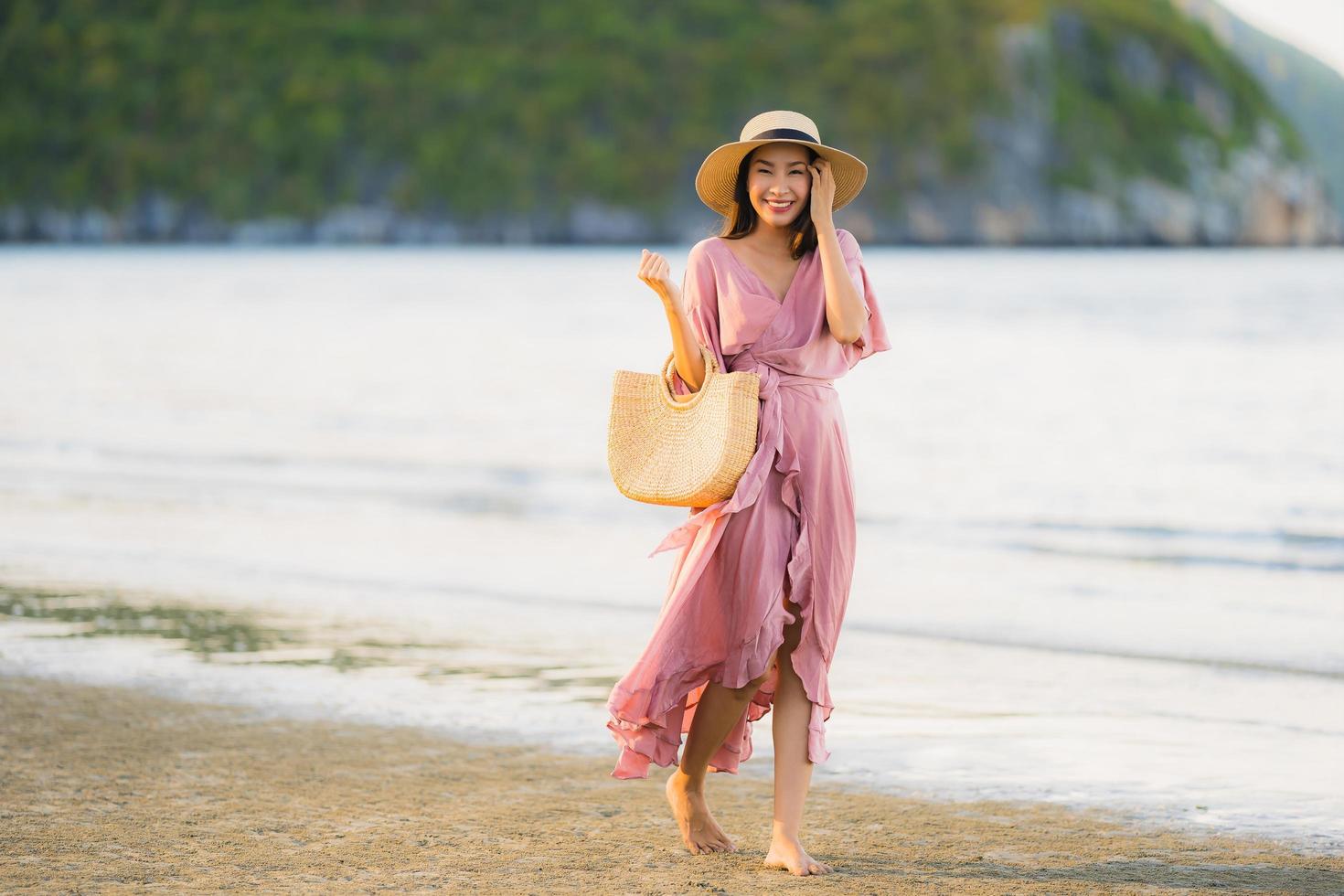 retrato jovem linda mulher asiática andar sorrindo e feliz na praia, mar e oceano foto