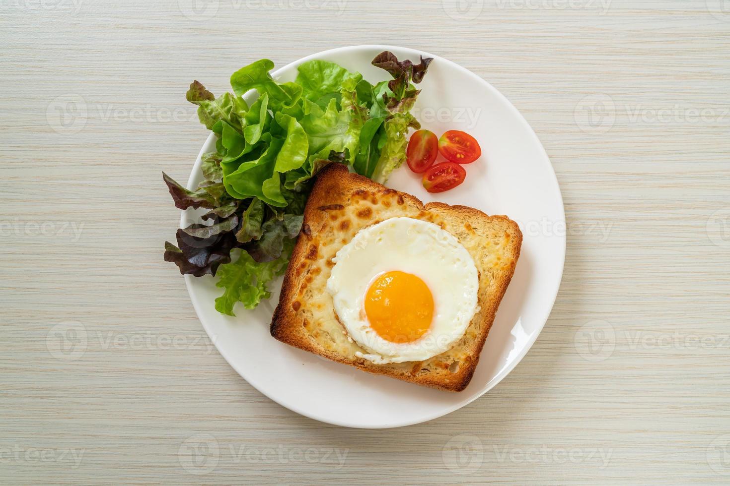 pão caseiro torrado com queijo e ovo frito por cima com salada de legumes no café da manhã foto