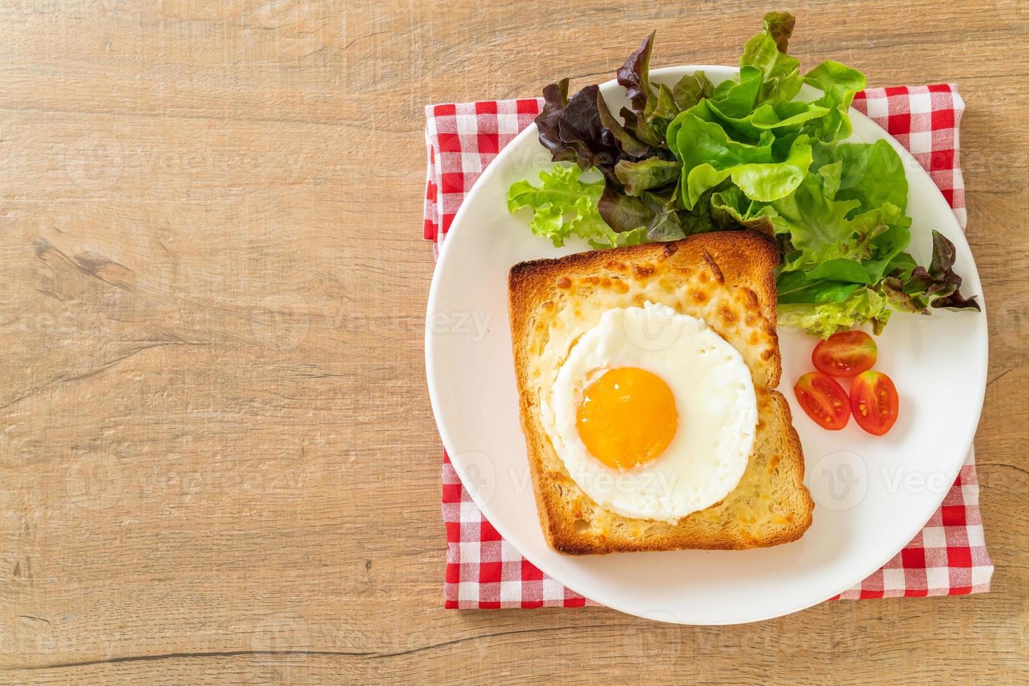 pão caseiro torrado com queijo e ovo frito por cima com salada de legumes no café da manhã foto