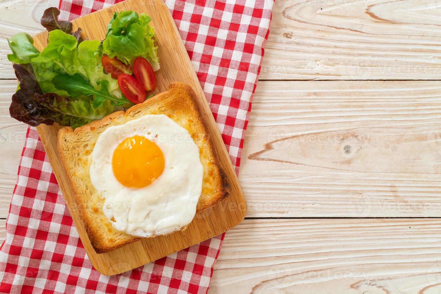 pão caseiro torrado com queijo e ovo frito por cima com salada de legumes no café da manhã foto