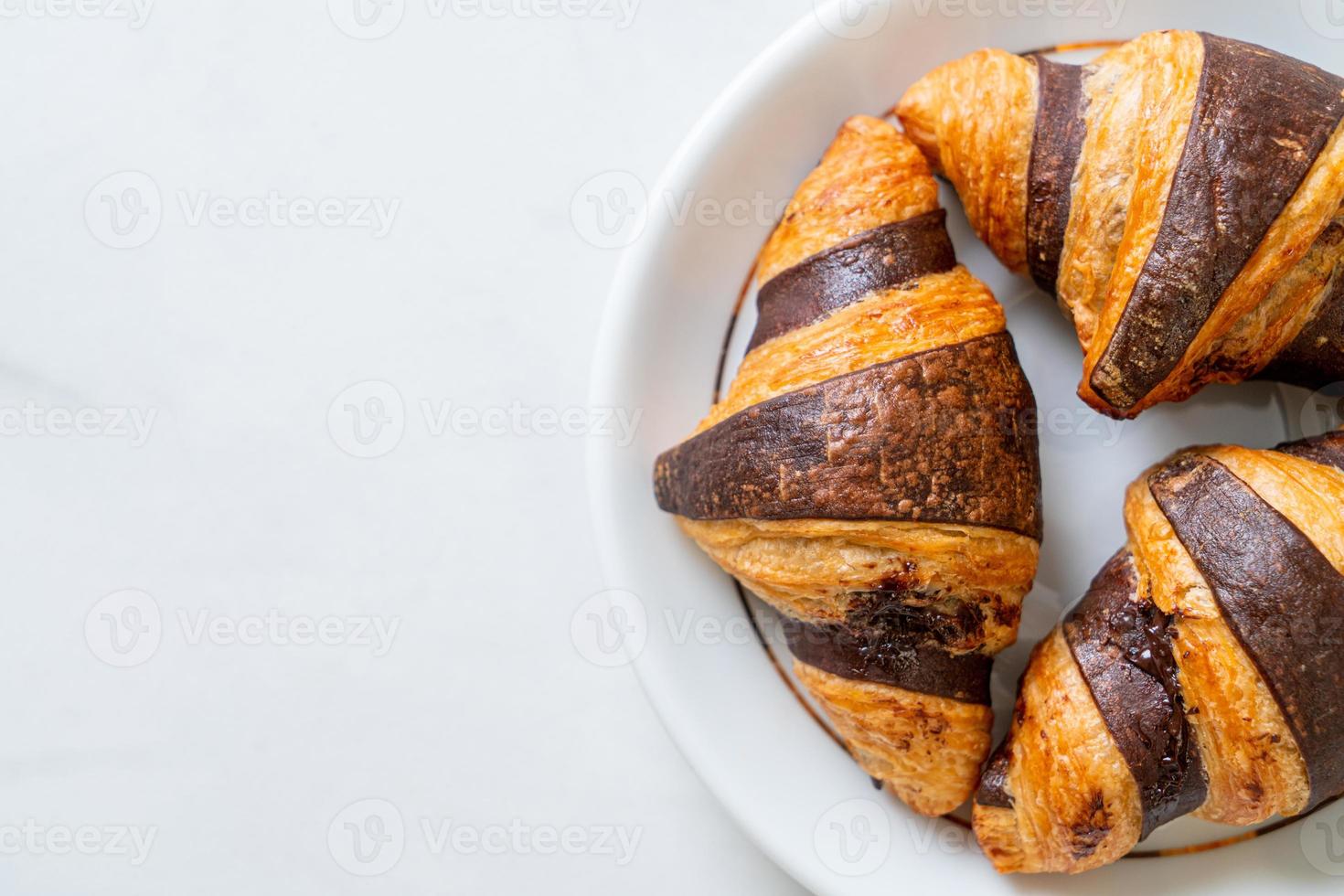 croissant fresco com chocolate no prato foto