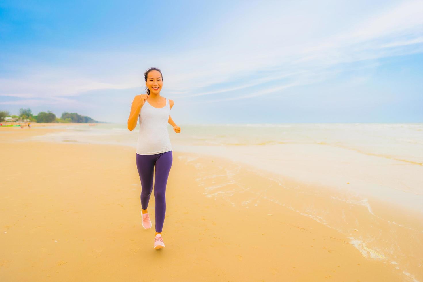 retrato bela jovem esporte mulher asiática exercício correndo e correndo na praia e no mar ao ar livre foto