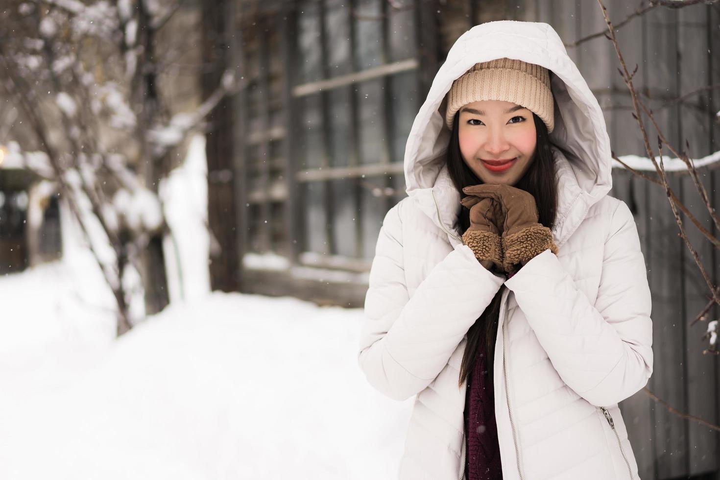 bela jovem asiática sorrindo feliz por viajar na neve, inverno foto
