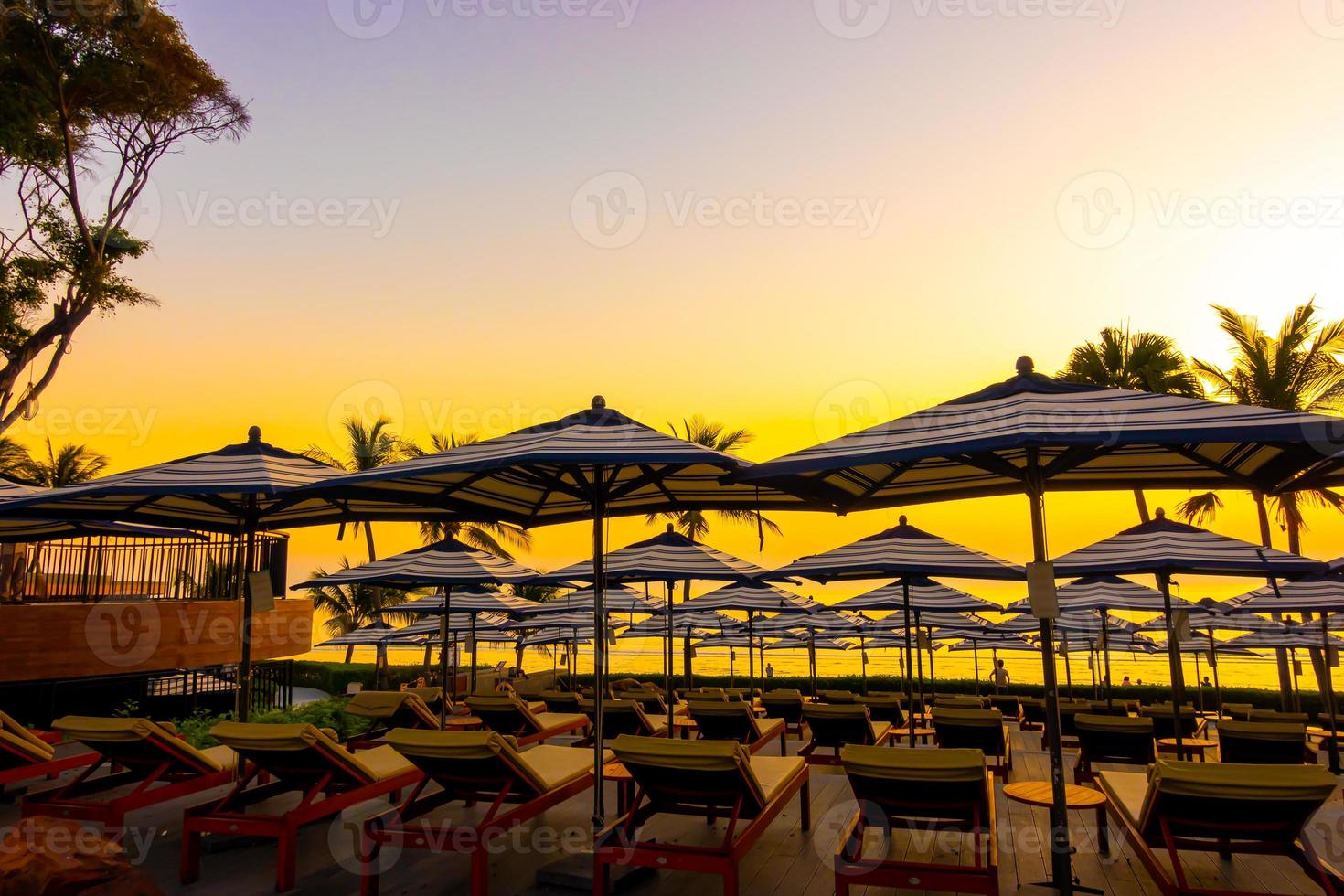 guarda-sóis e cadeiras ao redor da piscina externa em hotel resort para histórico de viagens de férias foto