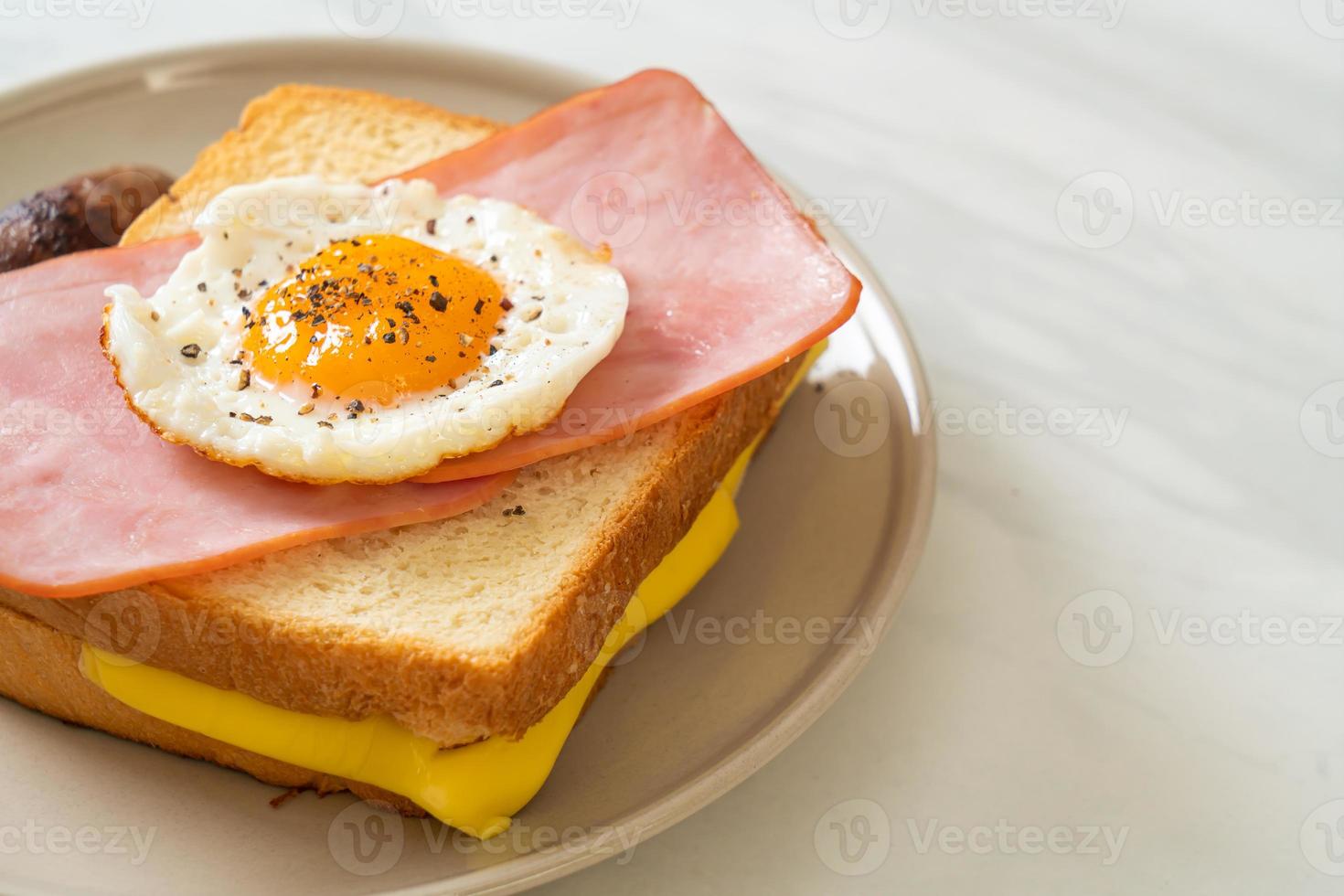 pão caseiro queijo torrado com presunto coberto e ovo frito com linguiça de porco no café da manhã foto