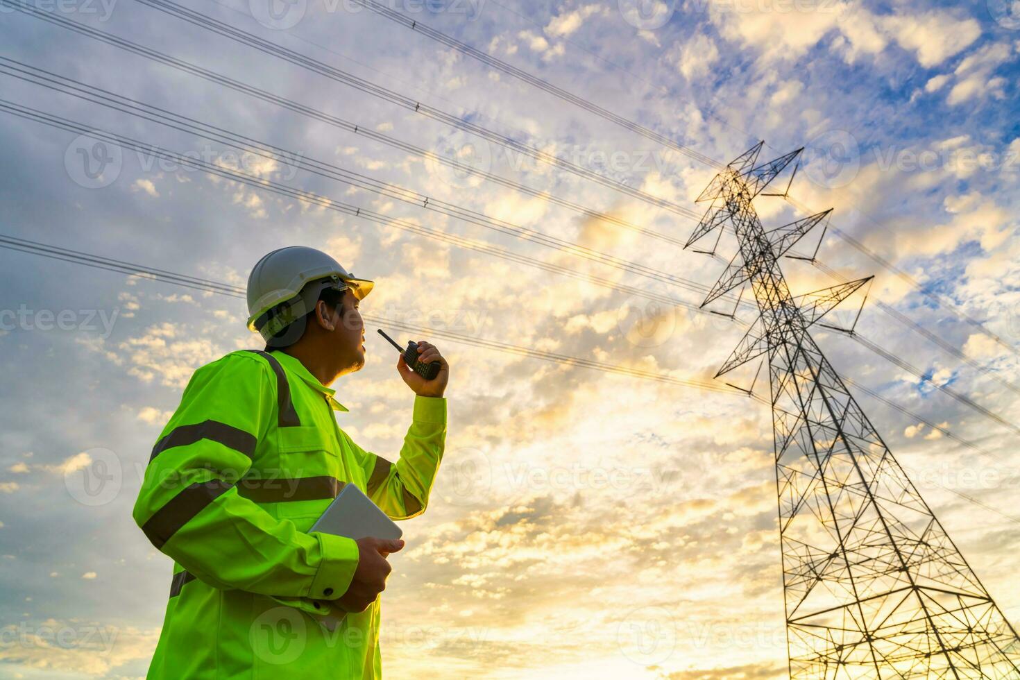 ásia engenheiro usar rádio Verificações às uma poder estação para planejamento trabalhos de gerando eletricidade a partir de uma alta voltagem transmissão torre às pôr do sol. foto