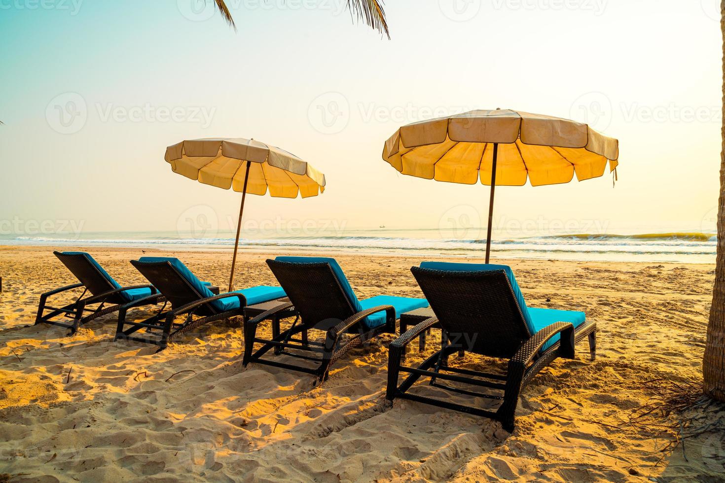 cadeira de praia guarda-sol com palmeira e praia do mar na hora do nascer do sol - conceito de férias e feriados foto