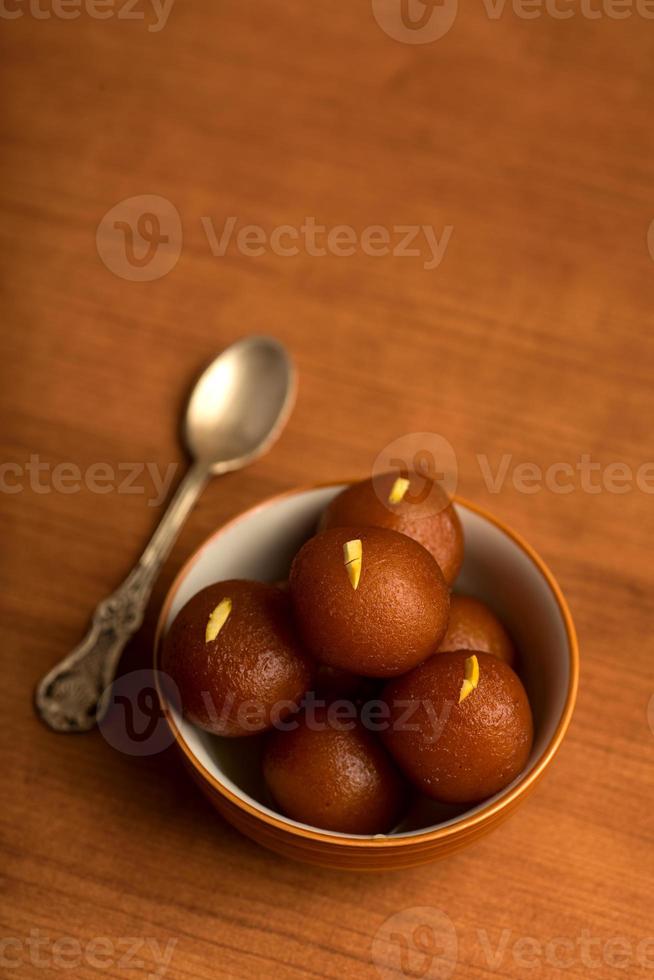 gulab jamun em tigela com fundo de madeira. sobremesa indiana ou prato doce. foto