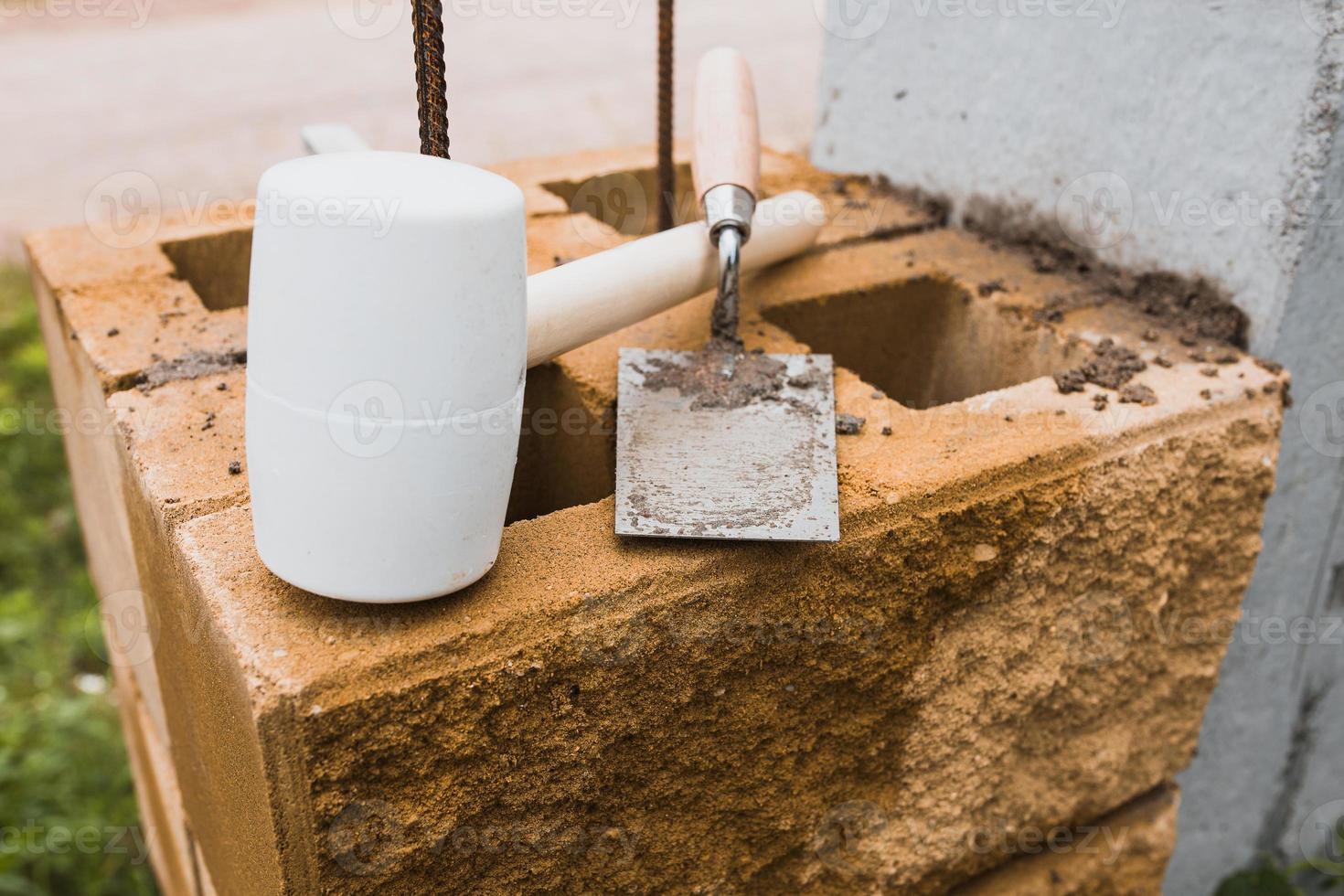 macete e pedreiro de espátula em um canteiro de obras - colocação de tijolos e telhas durante a construção e reparo foto