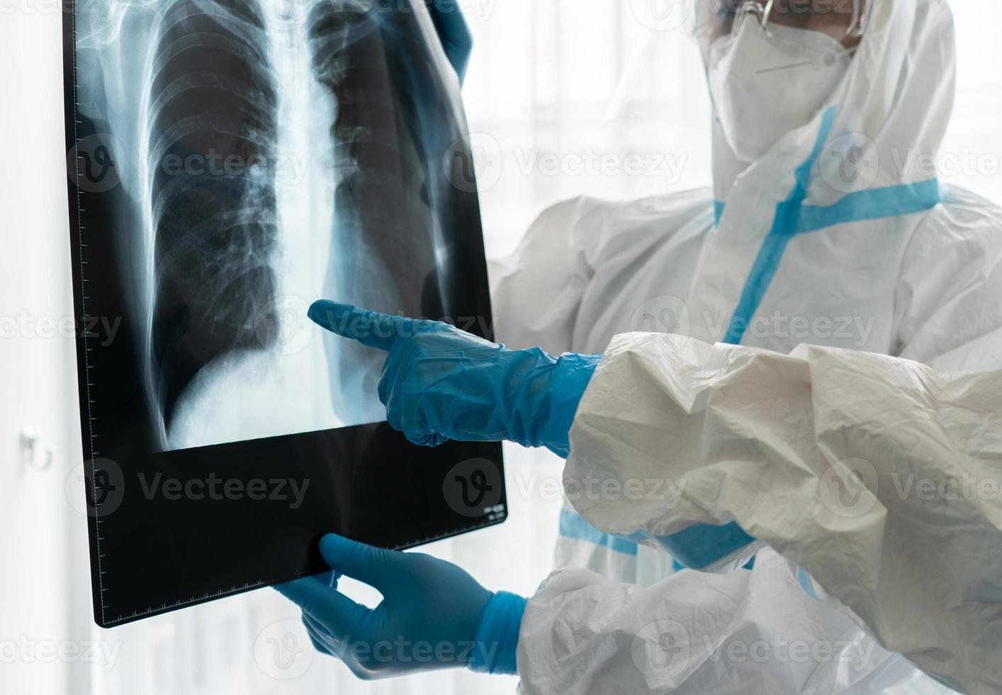 médicos em equipamentos de proteção individual ou ppe observando a radiografia de tórax de paciente asiática com infecção de covid-19 ou coronavírus na unidade de isolamento do hospital. conceito médico foto