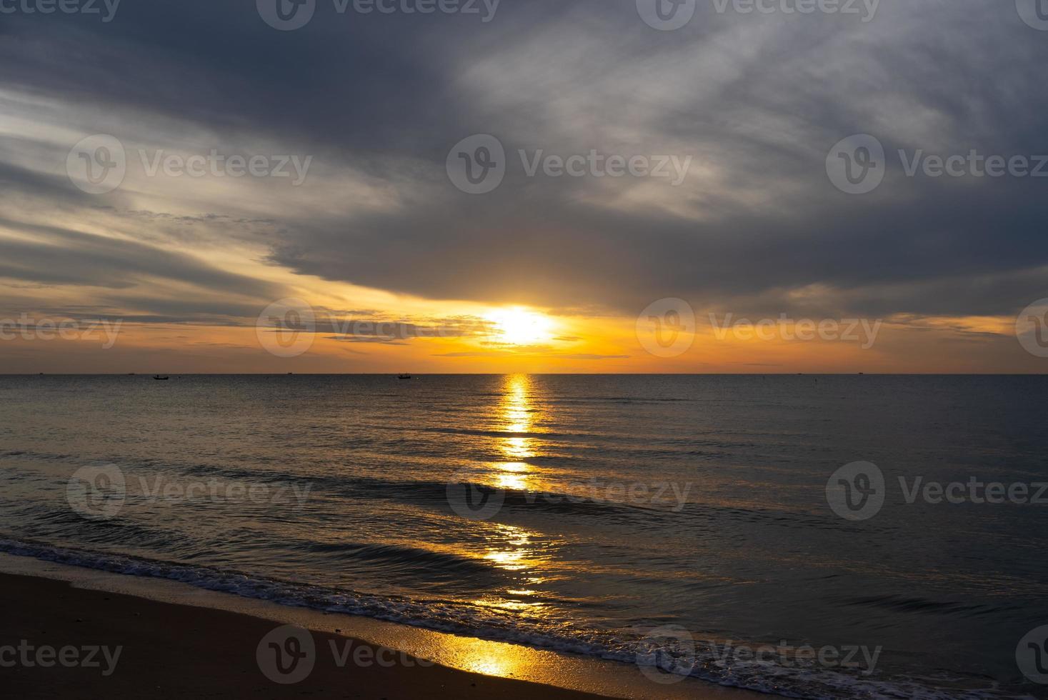 lindo pôr do sol na praia no verão com reflexo do sol na água foto